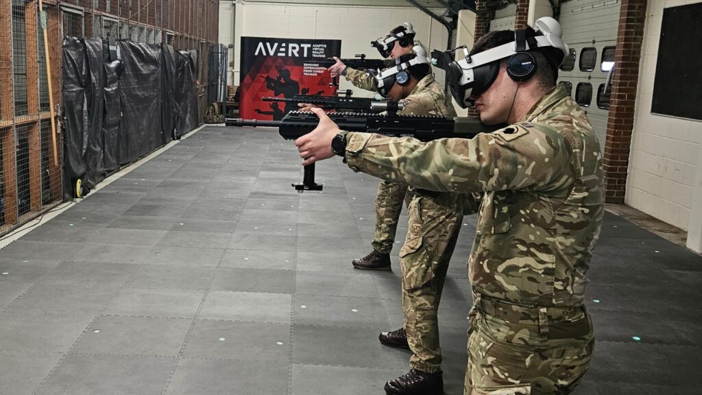 Three AVRT trainees in firing stance aiming tracked carbine surrogates on a multi-user marksmanship range